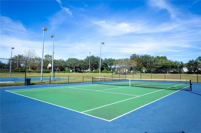 view of tennis court with community basketball court and fence