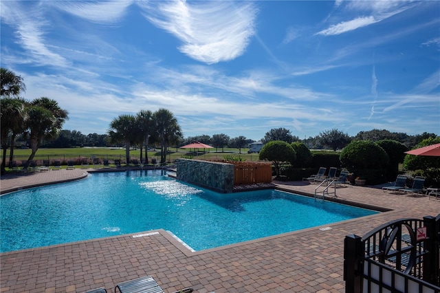 community pool with a patio area and fence