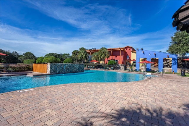 community pool with a patio area and fence