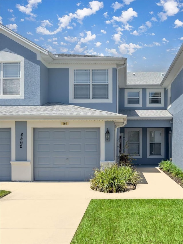 townhome / multi-family property featuring stucco siding, roof with shingles, concrete driveway, and an attached garage