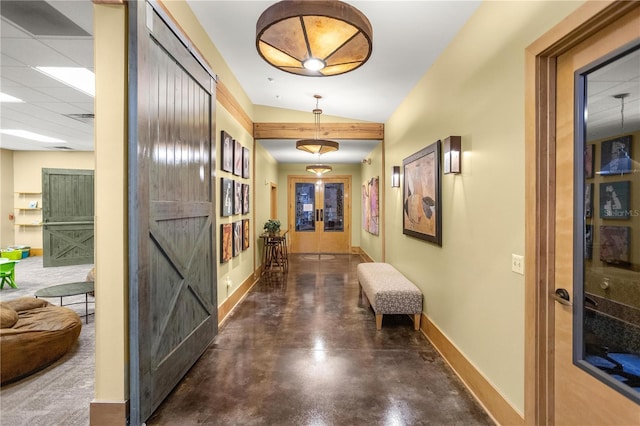 hallway featuring baseboards, vaulted ceiling, french doors, a paneled ceiling, and concrete flooring