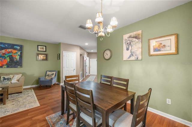 dining room with wood finished floors, visible vents, a chandelier, and baseboards