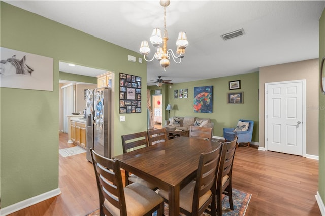 dining space with light wood-type flooring, baseboards, visible vents, and ceiling fan with notable chandelier