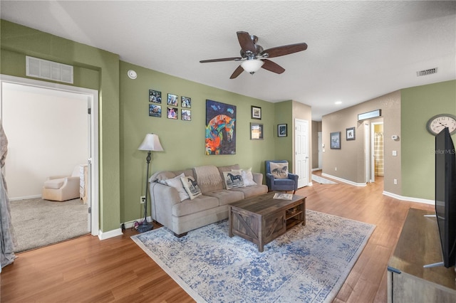 living room featuring visible vents, baseboards, and wood finished floors