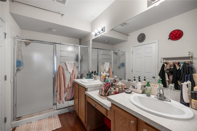 bathroom with a sink, double vanity, wood finished floors, and a shower stall