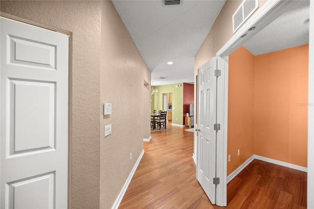 corridor featuring wood finished floors, visible vents, and baseboards