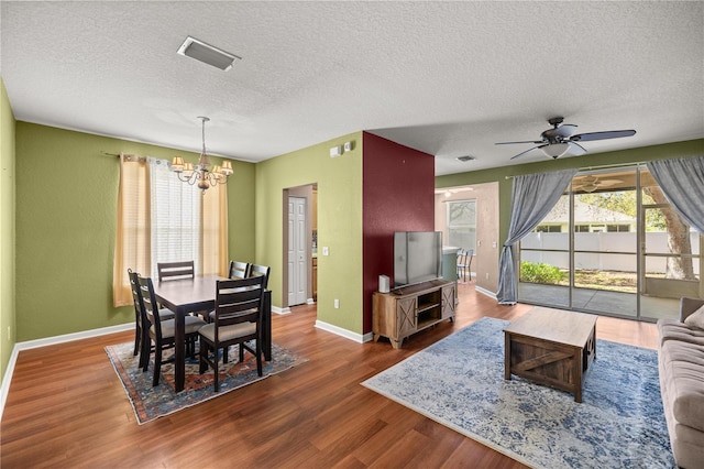 dining room with visible vents, baseboards, ceiling fan with notable chandelier, wood finished floors, and a textured ceiling