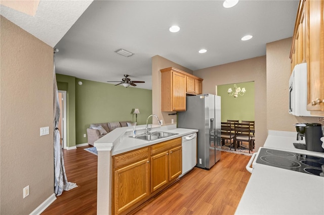 kitchen featuring open floor plan, light wood-style flooring, white appliances, and a sink