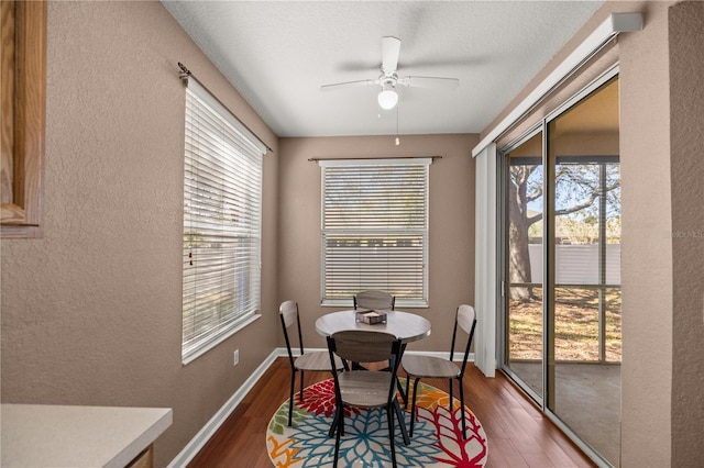 dining space with baseboards, wood finished floors, a ceiling fan, and a textured wall