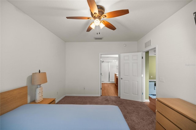 carpeted bedroom featuring baseboards, visible vents, ensuite bath, and a ceiling fan
