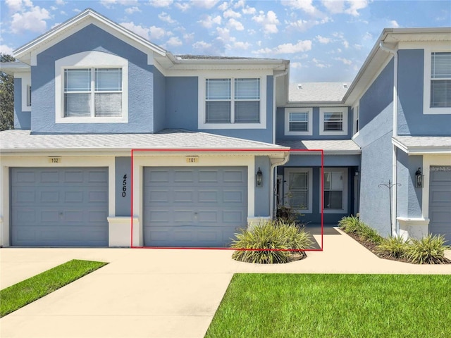 townhome / multi-family property with stucco siding, driveway, and an attached garage