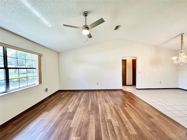 spare room with lofted ceiling, light hardwood / wood-style flooring, ceiling fan with notable chandelier, and a textured ceiling