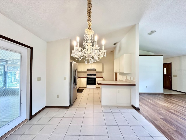 kitchen with light wood-type flooring, white range with electric stovetop, kitchen peninsula, stainless steel refrigerator with ice dispenser, and a textured ceiling