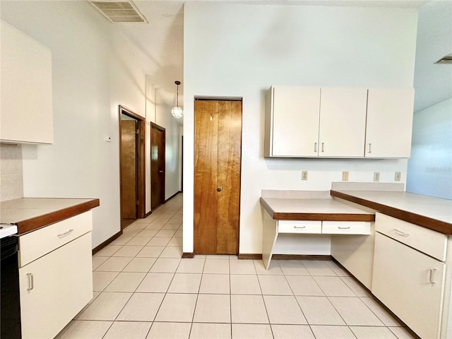 kitchen featuring light tile patterned floors, a high ceiling, and decorative light fixtures