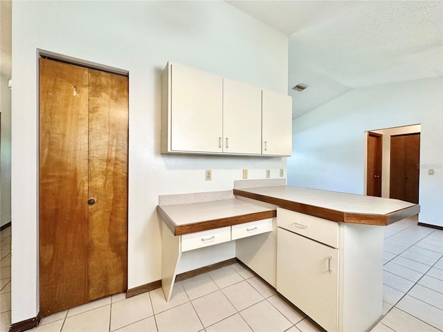 kitchen featuring lofted ceiling, kitchen peninsula, and light tile patterned floors