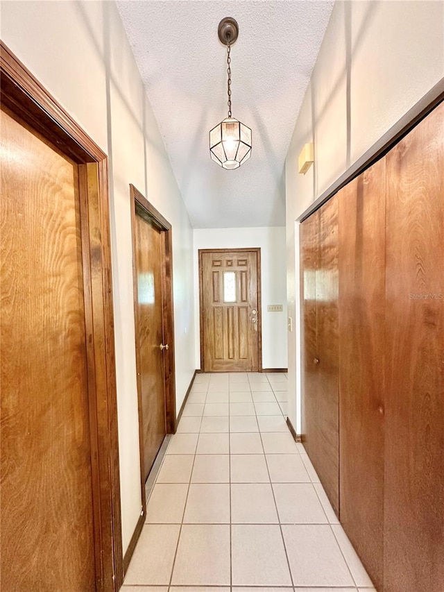 entryway featuring lofted ceiling, light tile patterned floors, and a textured ceiling