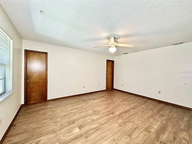 empty room with a textured ceiling, light hardwood / wood-style flooring, and ceiling fan