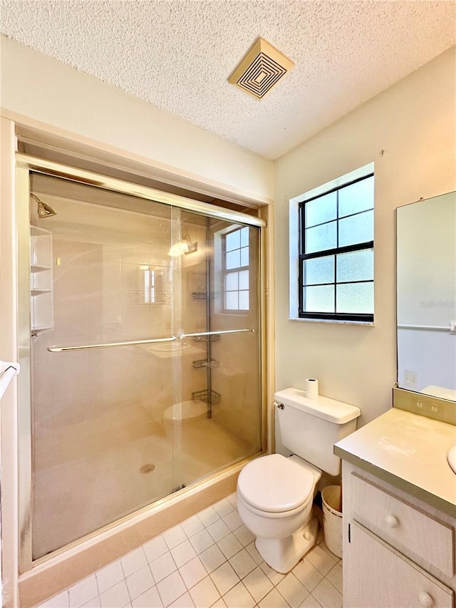 bathroom featuring a textured ceiling, tile patterned floors, toilet, a shower with shower door, and vanity