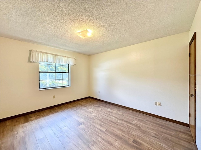 spare room featuring light wood-type flooring and a textured ceiling