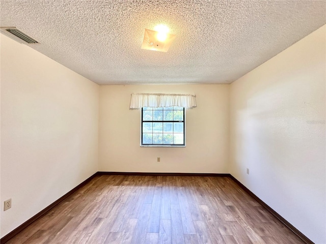 spare room with a textured ceiling and hardwood / wood-style flooring