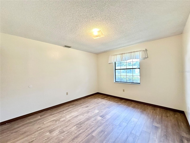 spare room featuring a textured ceiling and hardwood / wood-style floors