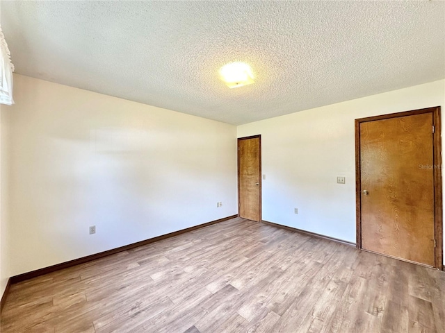 unfurnished room with light hardwood / wood-style floors and a textured ceiling