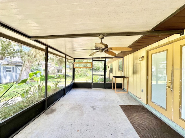 unfurnished sunroom with ceiling fan and beam ceiling