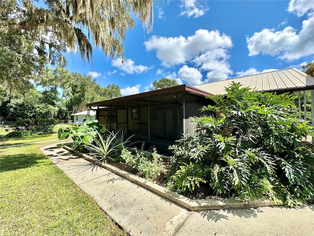 view of side of property with a sunroom and a lawn