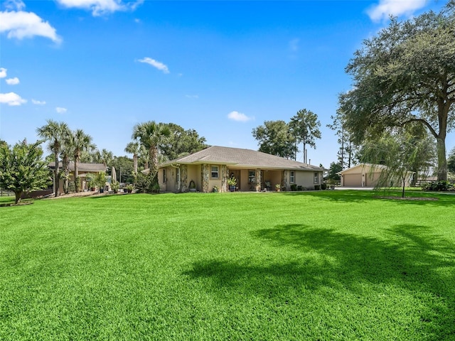 back of property featuring an outbuilding, a yard, and stucco siding