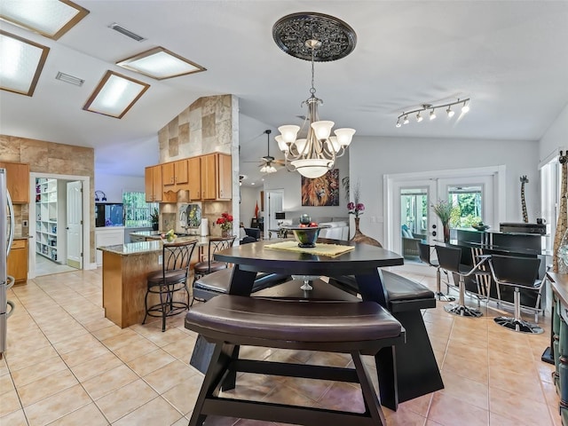 dining space featuring track lighting, light tile patterned floors, and vaulted ceiling