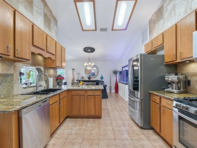 kitchen featuring light tile patterned floors, decorative backsplash, appliances with stainless steel finishes, a sink, and a peninsula