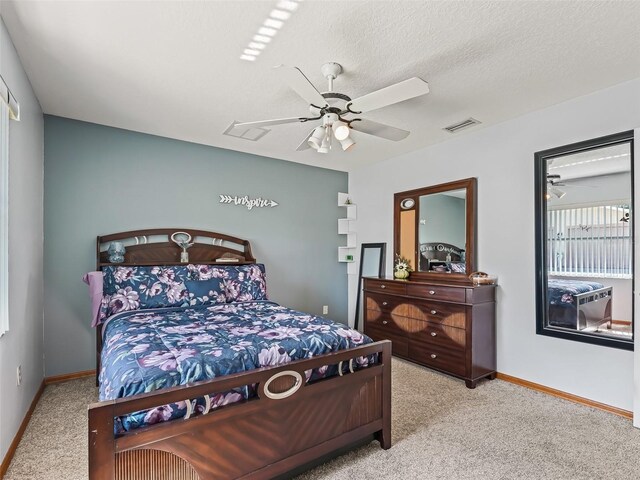 bedroom featuring a textured ceiling, light colored carpet, and ceiling fan