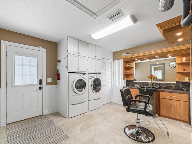 laundry room with light tile patterned floors, cabinets, independent washer and dryer, and a textured ceiling