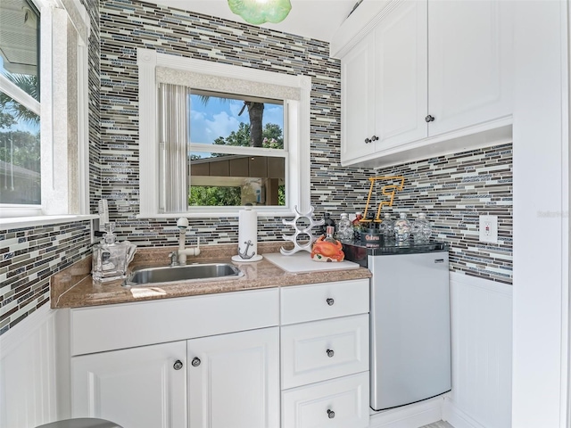 kitchen featuring tasteful backsplash, sink, and white cabinets