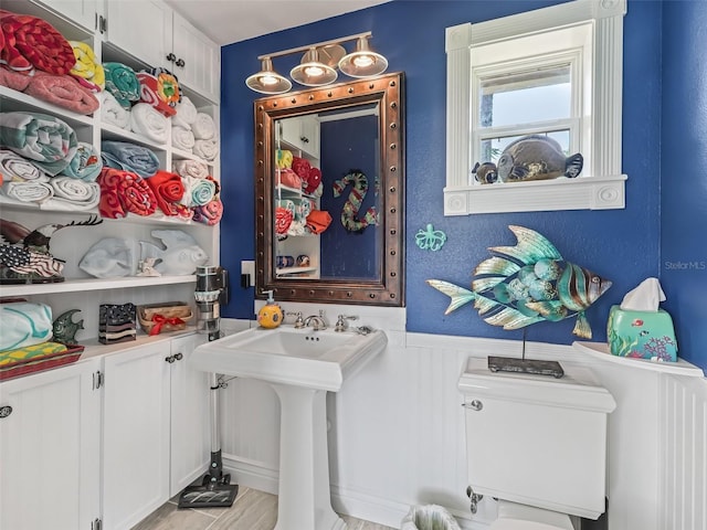 interior space with toilet and a wainscoted wall