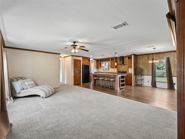 living room with a textured ceiling, crown molding, ceiling fan, and dark colored carpet