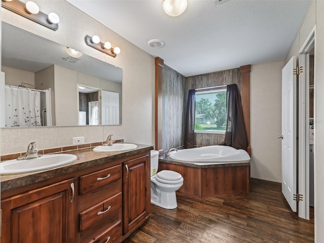 bathroom with hardwood / wood-style floors, toilet, a tub, vanity, and a textured ceiling