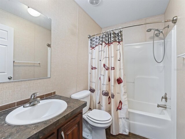 full bathroom featuring toilet, vanity, hardwood / wood-style flooring, a textured ceiling, and shower / tub combo with curtain