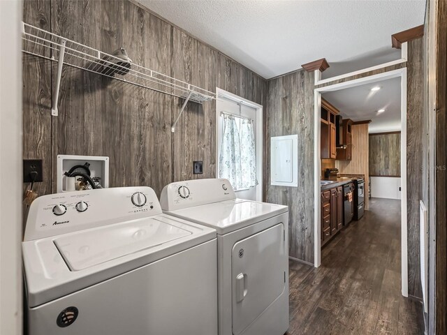 clothes washing area featuring a textured ceiling, dark wood-type flooring, wood walls, and washing machine and dryer