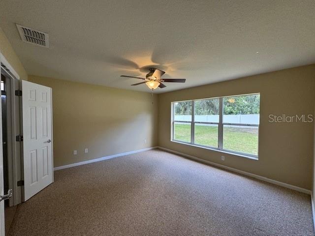 carpeted empty room with ceiling fan and a textured ceiling