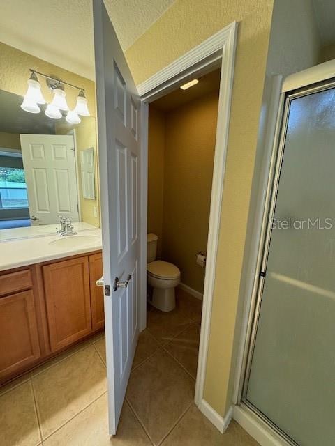 bathroom with toilet, an enclosed shower, tile patterned flooring, and vanity