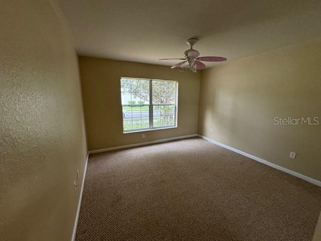 empty room featuring ceiling fan and carpet