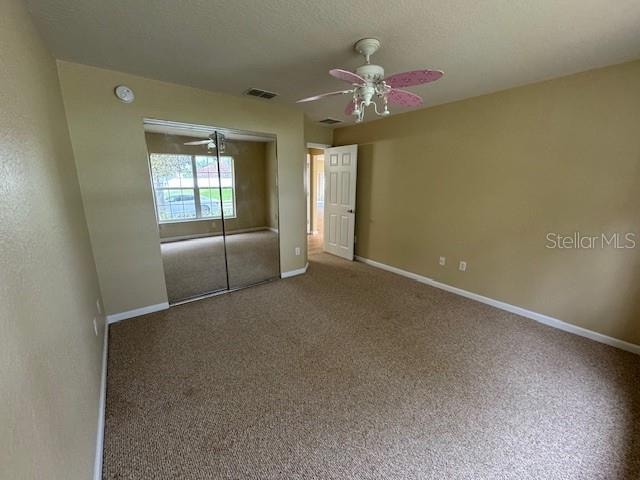 unfurnished bedroom featuring carpet flooring, ceiling fan, and a closet