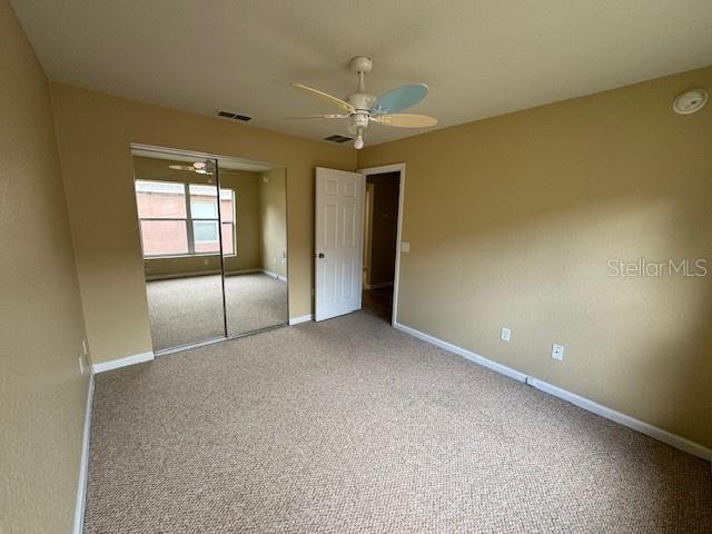 unfurnished bedroom with carpet floors, ceiling fan, and a closet