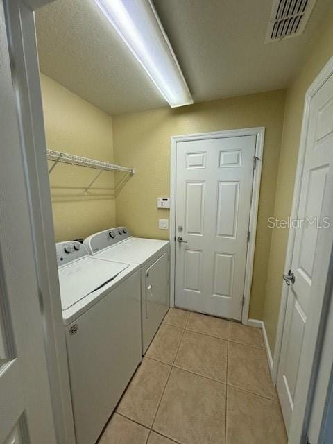 laundry area with washing machine and clothes dryer and light tile patterned flooring