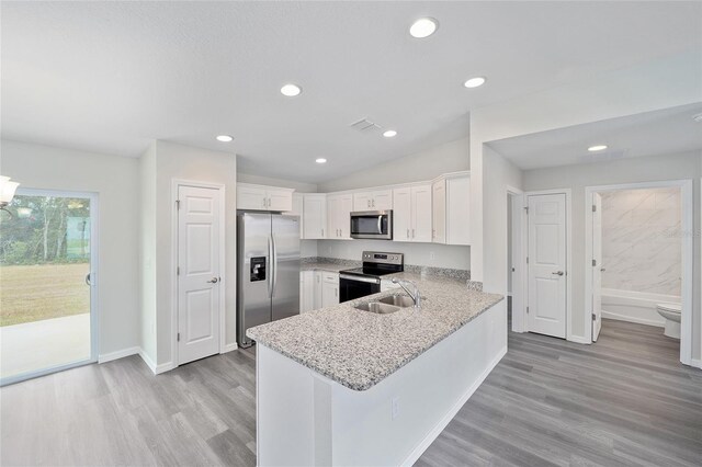 kitchen with light wood-type flooring, white cabinetry, kitchen peninsula, light stone countertops, and appliances with stainless steel finishes