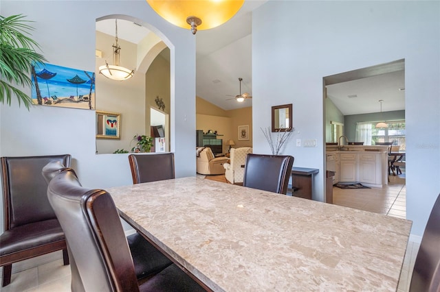 dining space featuring ceiling fan, sink, light tile patterned floors, and high vaulted ceiling