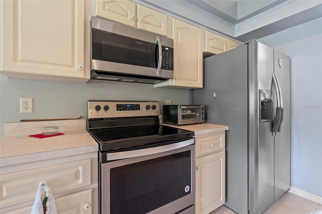 kitchen featuring stainless steel appliances, cream cabinets, and light tile patterned floors