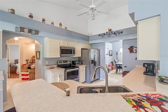 kitchen featuring light wood-type flooring, stainless steel appliances, sink, a high ceiling, and ceiling fan