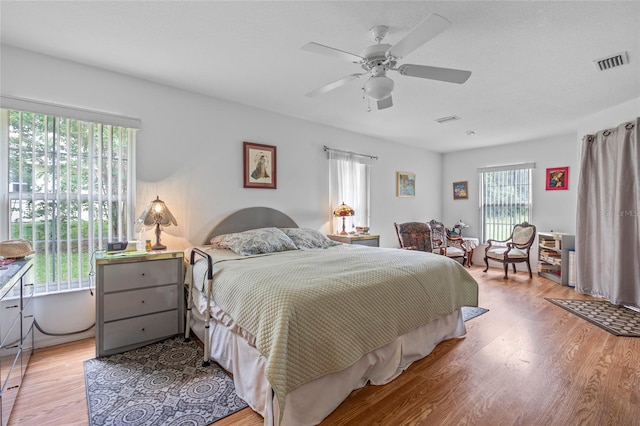 bedroom featuring ceiling fan, wood-type flooring, and multiple windows